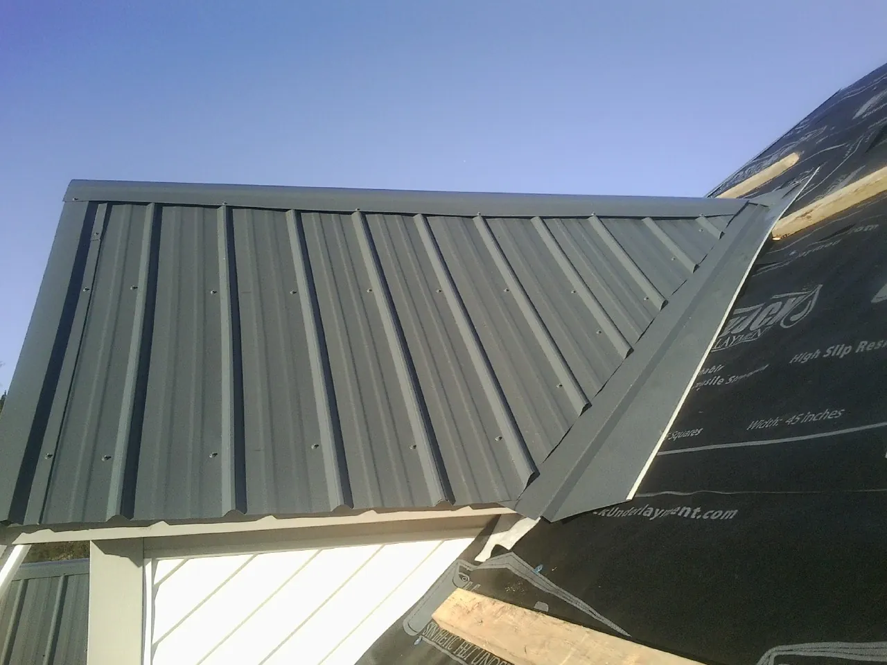 Gray metal roof panels going on over a garage gable in Antelope