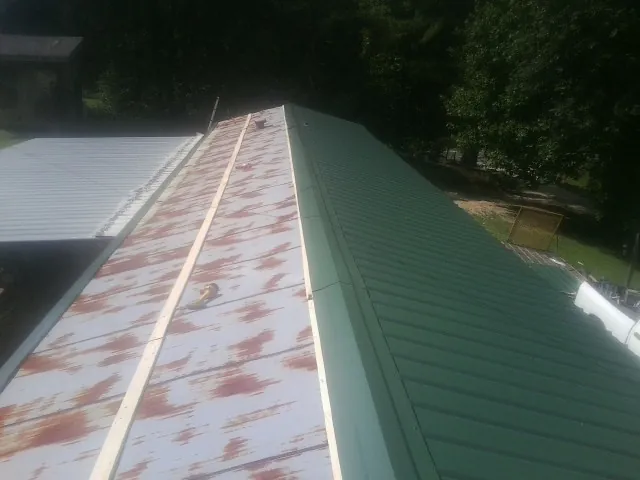 Old rusted panels beside newly installed green metal roofing — Wind Damage Roof Repair by Roofing Brothers in Antelope
