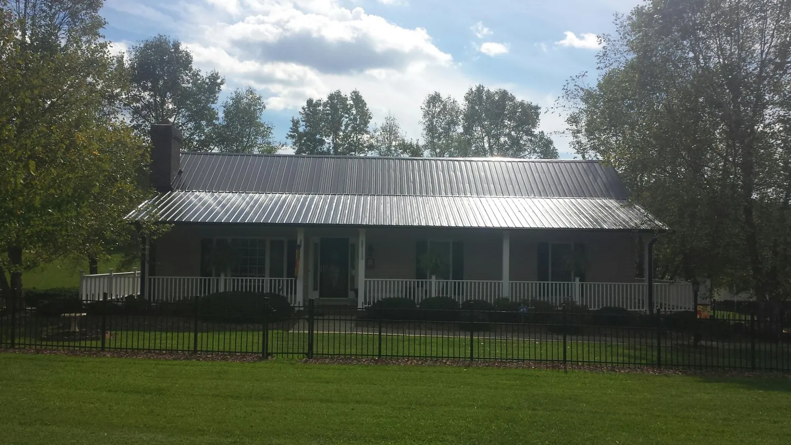 Gray metal roof on a brick ranch with a full width front porch — Gutter Guard Installation work by our crew in Antelope