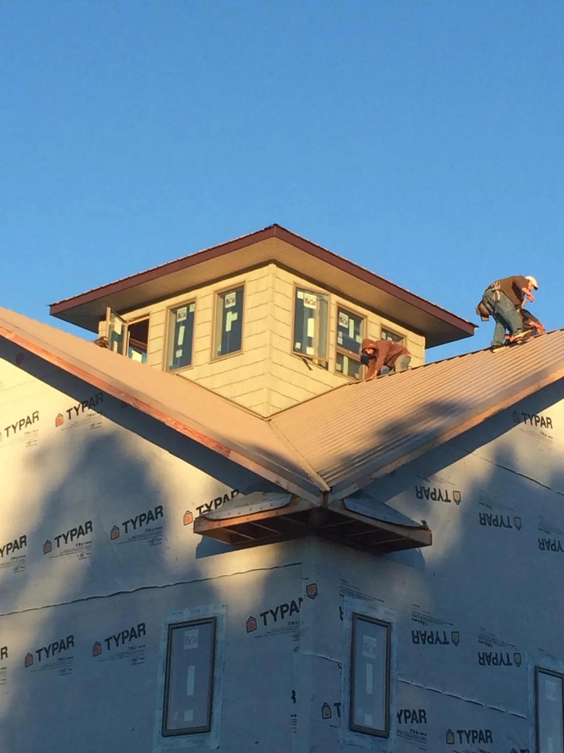 Roofers working around a rooftop cupola on a new metal roof at sunset — Roof Waterproofing in Antelope by Roofing Brothers